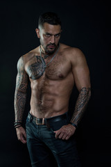 Obraz na płótnie Canvas Sport or fitness and bodycare. Bearded man with fit tattooed body. Man with sexy bare torso in jeans. Tattoo model with six pack and ab. Athlete or sportsman with muscular chest and belly