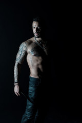 Fototapeta na wymiar Athlete or sportsman with muscular chest and belly. Tattoo model with six pack and ab. Bearded man with tattooed body. Man with sexy bare torso in jeans. Sport or fitness and bodycare