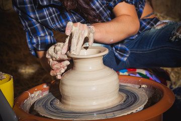 ceramic workshop - girl makes jug of clay on potter's wheel.