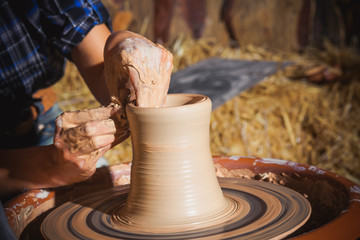 Fototapeta na wymiar hands closeup, girl makes jug of clay on potter's wheel.