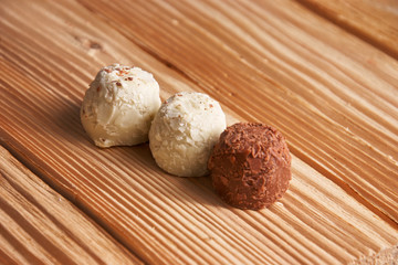Macro. White and milk chocolate candies on a light wooden background