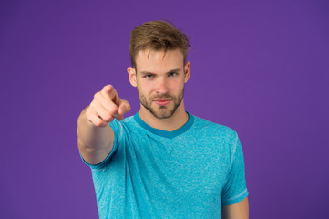 Fashion athlete point finger on violet background. Athletic man in blue tshirt on purple backdrop. Sportsman with beard on unshaven face skin. Skincare and barber salon. Sport or fitness and wellness