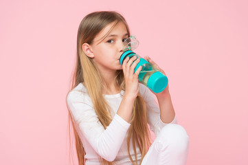 Obraz premium Thirsty kid drink water for health on pink background. Child hold water bottle. Little girl with plastic bottle. Thirst and dehydration. Childhood activity and energy, punchy pastel trend