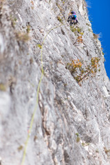 Young man lead climbing on cliff