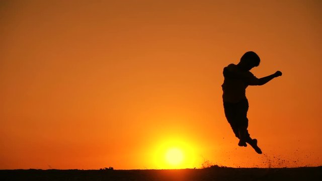 silhouette of boy jumping at sunset