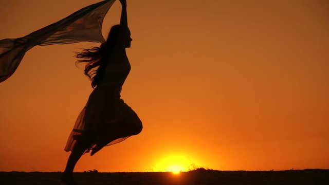 Silhouette of young girl walking against sunset
