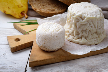 French goat cheese: Crottin de Chavignol and Chabichou du Poitou on wooden chopping board.
