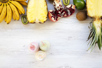 Fruit smoothies of different tastes in glass jars on white wooden background, top view, from above.