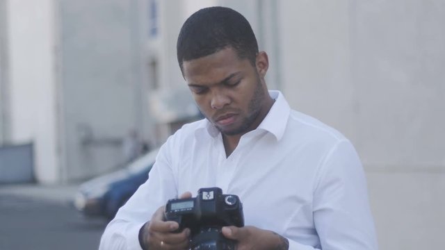 African American photographer takes a photo with his camera outdoor at city background