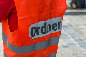 Ein Mann mit einer Warnweste mit dem deutschen Wort - Ordner, Deutschland