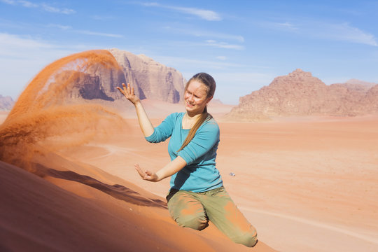 young woman with a smile sprinkled sand in the desert