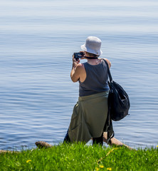 Obraz premium Woman on the beach of lake makes some photos