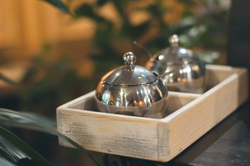 Close-up of silver sugar bowl on wooden table at caffe. Cosy autumn concept. Stylish toning, place for text.