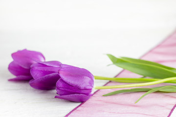 A bunch of purple tulips on a white wooden table.