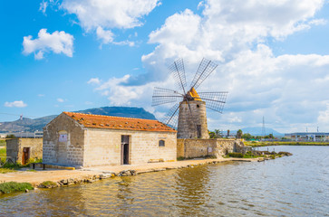 View of a windmill in the Saline di Trapani e Paceco natural reserve near Trapani, Sicily, Italy - obrazy, fototapety, plakaty