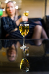 A glass of white wine against the background of a girl with a glass. The concept of going to a restaurant with a girl