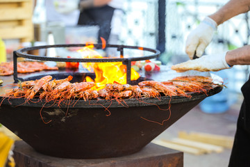 A street cook prepares shrimp near the fire