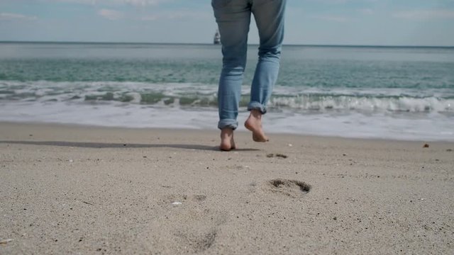 Bare women's feet walking towards the sea