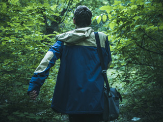 young man walking in dark dense rainforest on the path