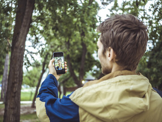 young man in jacket making a selfie outdoors with his smartphone