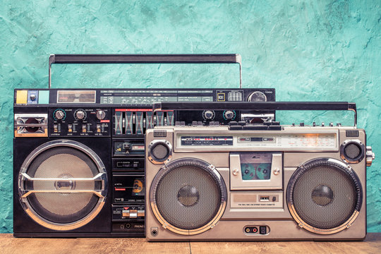 Retro designed ghetto blaster stereo boombox radio receivers with cassette recorders from circa 80s front textured aquamarine wall background. Listening music concept. Vintage old style filtered photo