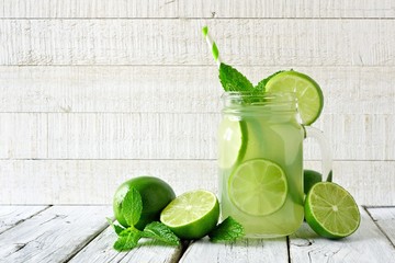 Homemade limeade in a mason jar glass. Side view on a rustic white wood background.