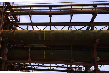 Abandon rough rust red painted structure of steel pipelines construction and metal tanks in industrial manufacturing  plant .