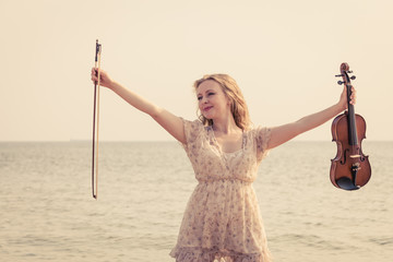 Woman on beach near sea holding violin