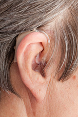 Closeup senior woman using hearing aid