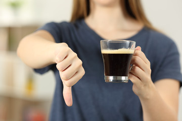 Woman hands holding a coffee cup with thumbs down - obrazy, fototapety, plakaty