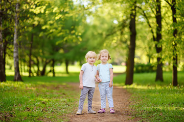 Fototapeta premium Cute little children playing together and holding hands in sunny summer park
