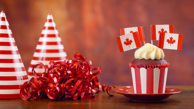 Red and white theme cupcakes with Canadian maple leaf flags for first of July Canada Day or Canadian theme party food.