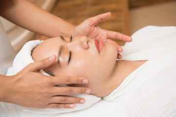 Fototapeta na wymiar Face massage. Spa skin and body care. Close-up of young woman getting spa massage treatment at beauty spa salon. Facial beauty treatment.
