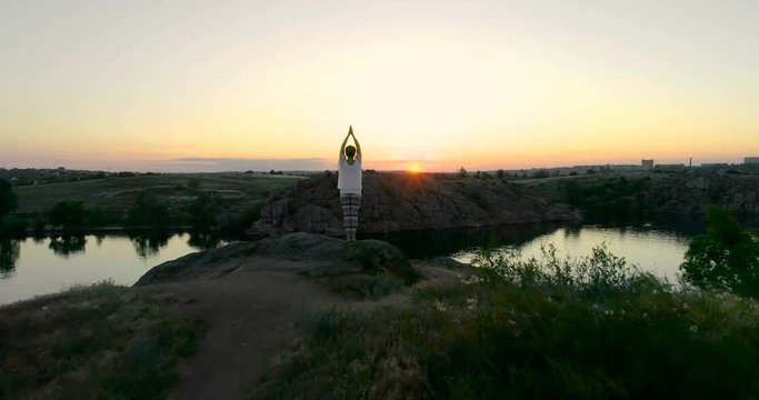 Girl standing on the edge of a rock and meditates