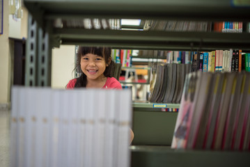 Cute little girl studying at the library and smiling