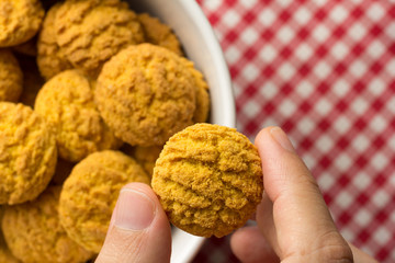 Delicious yellow cookie of corn. Sweet food of Festa Junina, a typical brazilian party. Hand picking up a snack.