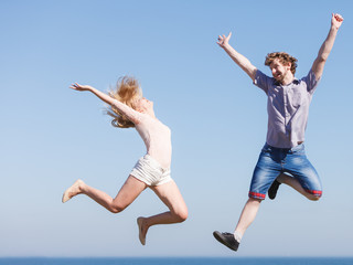 Carefree couple jumping against blue sky