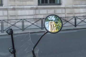 The mirror of a motorcycle reflecting the image of a tower of the Notre Dame Cathedral in Paris
