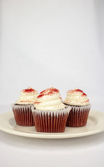 Yummy red velvet cupcakes with white icing and sprinkles on an isolated white background