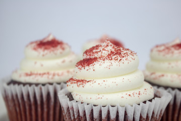 Yummy red velvet cupcakes with white icing and sprinkles on an isolated white background