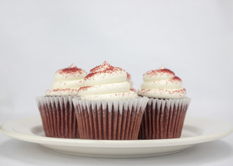 Yummy red velvet cupcakes with white icing and sprinkles on an isolated white background