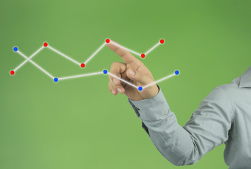 businessman hand pointing to the top line of a graph on green background.