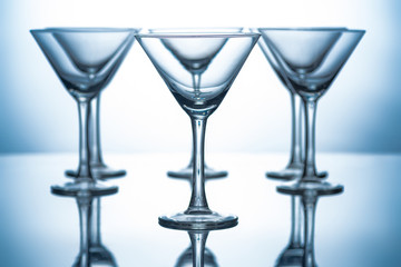 row of empty martini glasses on grey with reflections