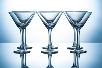 row of transparent martini glasses on grey with reflections