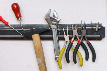 Set of tanner tools close-up. An awl, screwdriver, hammer, wrench, pliers and wire cutters hang on...