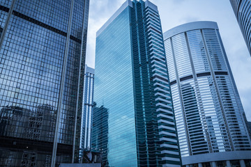 Bottom view of modern skyscrapers in business district against blue sky