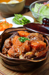 A bowl of beef stew on a wooden table 