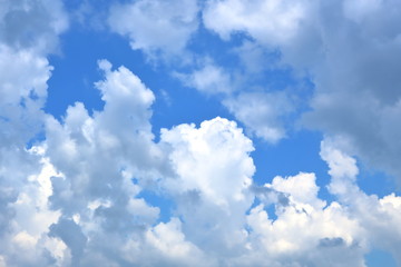 Deep blue sky covered by white fluffy cumulus clouds