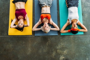 elevated view of multicultural female athletes exercising on fitness mats at gym