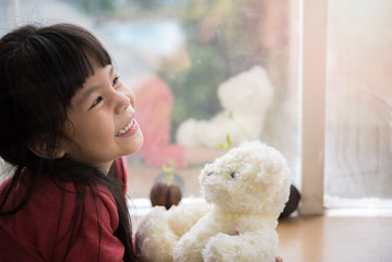 child little girl by the window with a teddy bear